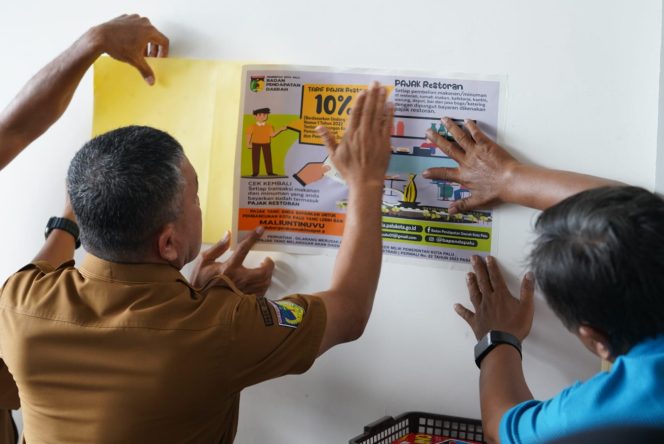 
					Wali Kota Palu, Hadianto Rasyid menempelkan stiker pemberitahuan bayar pajak bagi restoran. Photo: Humas Pemkot Palu