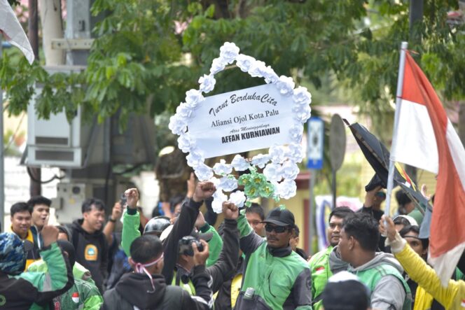 
					Sejumlah pengemudi ojek online di Palu mengangkat karangan bunga bertuliskan belasungkawa untuk Affan Kurniawan saat aksi solidaritas di depan Gedung DPRD Sulawesi Tengah, Senin (01/09/25). FOTO: netiz.id 