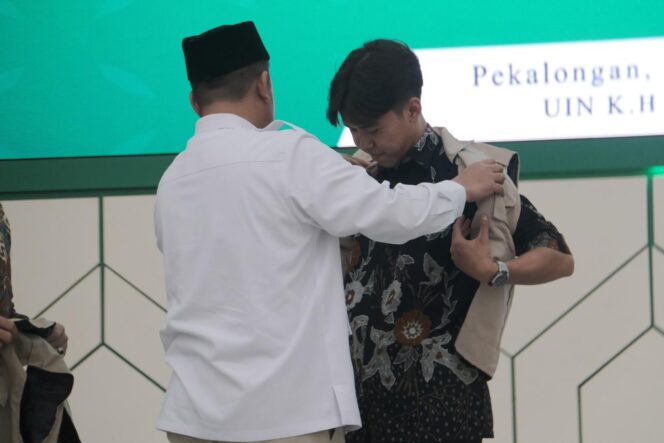 
					Menteri Agraria dan Tata Ruang/Kepala Badan Pertanahan Nasional (ATR/BPN) Nusron Wahid mengenakan atribut KKN kepada salah satu mahasiswa Universitas Islam Negeri (UIN) K.H. Abdurrahman Wahid Pekalongan saat pelepasan peserta KKN Tematik Ekoteologi dan Pertanahan di Kampus 2 UIN Pekalongan, Senin (13/10/25). FOTO: istimewa