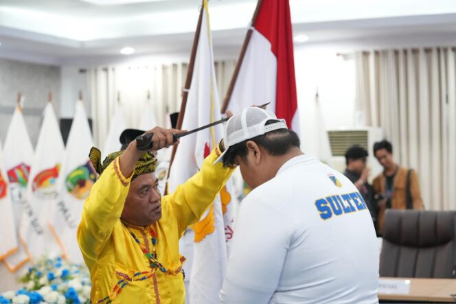 
					Seorang tokoh adat Kaili menempelkan senjata tradisional Guma ke pundak atlet Sulawesi Tengah dalam prosesi adat Mompakaroso pada acara pelepasan kontingen PON Beladiri 2025 di Ruang Polibu, Kantor Gubernur Sulteng, Kamis (09/10/25). FOTO: istimewa