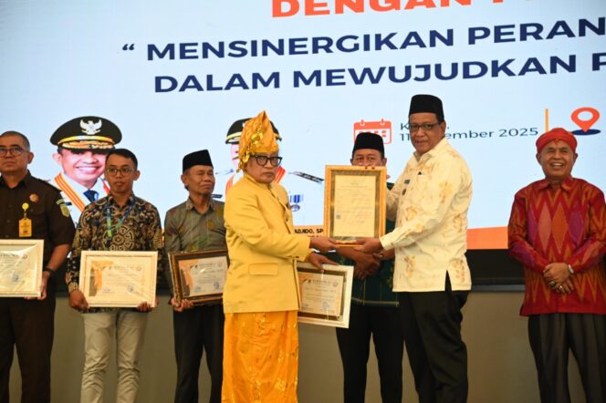 
					Asisten Pemerintahan dan Kesra Provinsi Sulawesi Tengah, Dr. Fahrudin, menyerahkan piagam penghargaan kepada salah satu tokoh adat pada Rapat Sinkronisasi Program Pelibatan Lembaga Adat dengan Pemerintah Daerah, Kamis (11/12/25). FOTO: istimewa